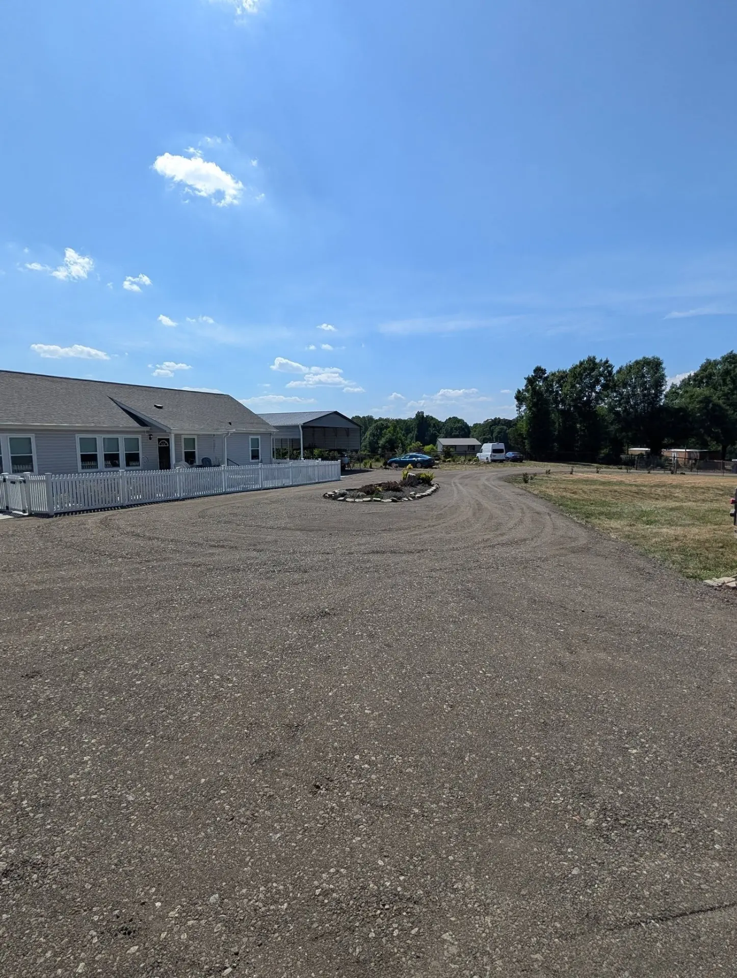Freshly graded gravel driveway and turnaround in front of a ranch home