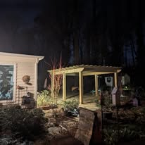 Pergola and landscape lighting installed beside a home at night