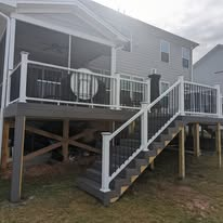 Elevated composite deck with white railing, black balusters, and staircase beside a screened porch