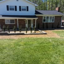 Front yard regraded with new shrub beds along a brick two-story home