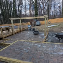 Paver patio under construction with pergola frame and fire pit