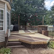 Multi-level wood deck with two-tone decking and string lights in a backyard