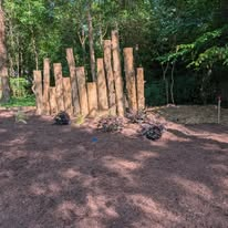 Cleared and mulched wooded area with new wood privacy fence posts set