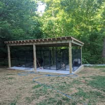 Three-stall covered dog kennel with wire mesh panels in a cleared backyard
